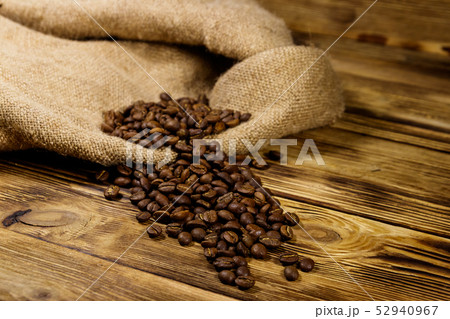 Roasted coffee beans on sackcloth on wooden table 52940967