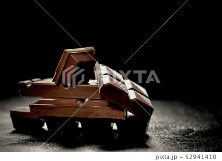 Cracked dark chocolate bar at black background 52941410