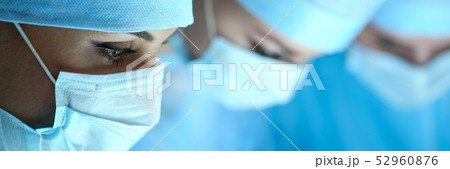 Three surgeons at work operating in surgical theatre Three surgeons at work operating in surgical theatre 52960876