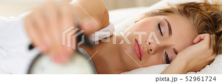 Sleepy young woman trying kill alarm clock 52961724