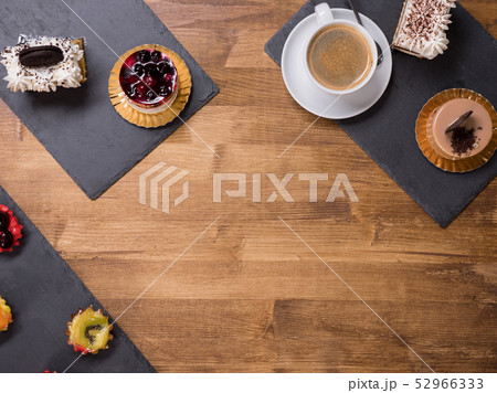 Top viwe of a cup of coffee with different cakes with different flavours over a wooden table Top viwe of a cup of coffee with different cakes with different flavours over a wooden table 52966333