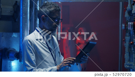 Scientist checking equipment and using tablet 52970720