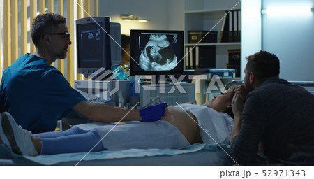 Couple watching ultrasound image of future child Couple watching ultrasound image of future child 52971343