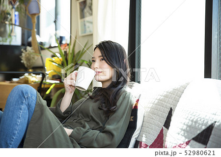 女性　若い女性　リビング　ソファ　ライフスタイル　リラックス　スマイル　笑顔　 52980621
