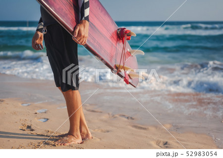 man with a surfboard in his hands against the background of the ocean beach, active lifestyle man with a surfboard in his hands against the background of the ocean beach, active lifestyle 52983054