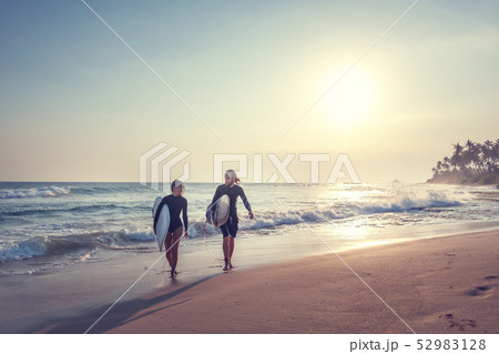 Young beautiful couple friends on ocean with surfboards in their hands, sports, active lifestyle Young beautiful couple friends on ocean with surfboards in their hands, sports, active lifestyle 52983128