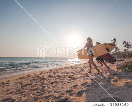 Young couple of happy smiling surfers run with surfboards on ocean coast, sport active lifestyle Young couple of happy smiling surfers run with surfboards on ocean coast, sport active lifestyle 52983140