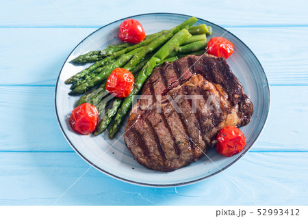 Grilled beef steak ribeye with cherry tomatoes and 52993412