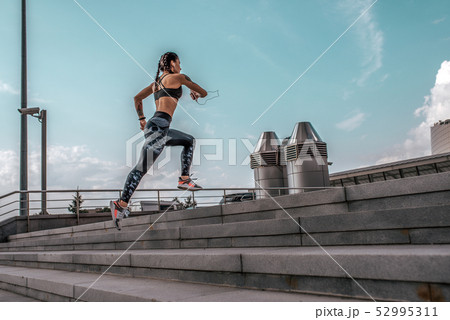 Athlete woman runs jump sports jogging training summer city. Headphones telephone. Concept fitness Athlete woman runs jump sports jogging training summer city. Headphones telephone. Concept fitness 52995311