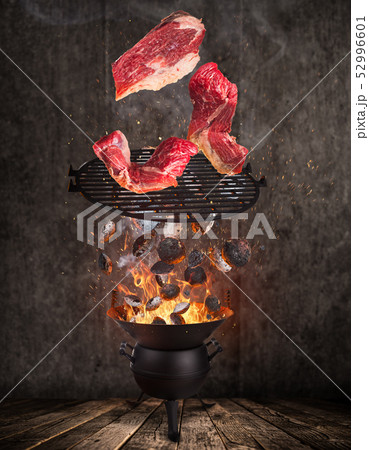 Tasty beef steaks flying above cast iron grate with fire flames. Tasty beef steaks flying above cast iron grate with fire flames. 52996601