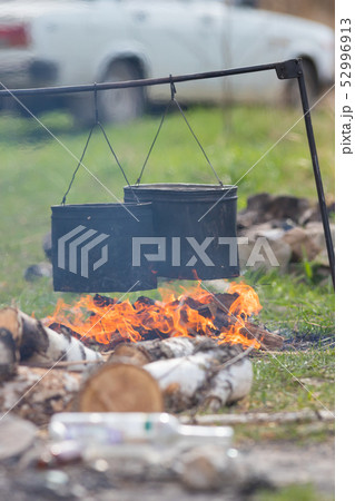 People heating up water in the metal buckets using a bonfire. Buckets hanging on the crossbar People heating up water in the metal buckets using a bonfire. Buckets hanging on the crossbar 52996913