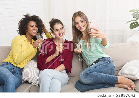 Girls taking selfie, drinking champagne at home 52997042