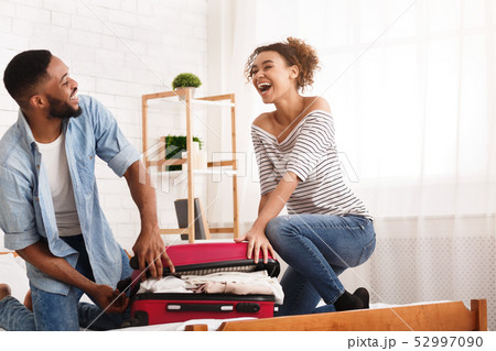 African-American Couple Laughing And Trying To Close Valise African-American Couple Laughing And Trying To Close Valise 52997090