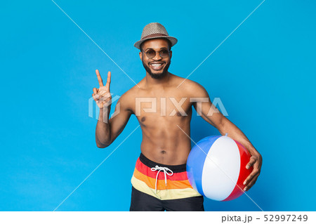 Shirtless black guy holding inflatable ball, showing v sign 52997249