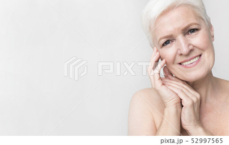 Portrait of charming nude senior woman touching her skin 52997565