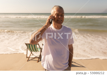 Senior man talking on mobile phone at beach Senior man talking on mobile phone at beach 53000212