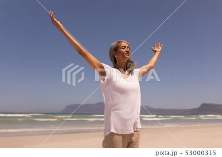 Senior woman with arms outstretched standing on beach Senior woman with arms outstretched standing on beach 53000315