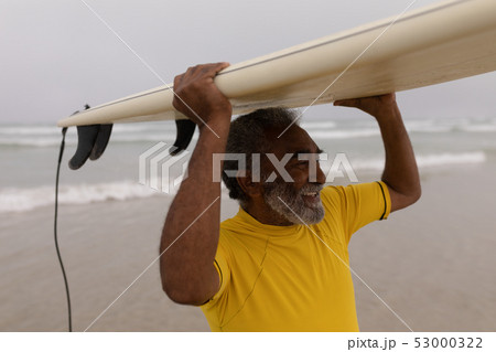 Senior male surfer carrying the surfboard on his head at beach 53000322