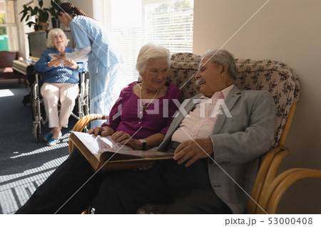 Front view of senior couple looking photo album on sofa Front view of senior couple looking photo album on sofa 53000408