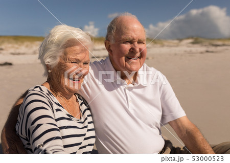 Happy senior couple sitting on beach Happy senior couple sitting on beach 53000523