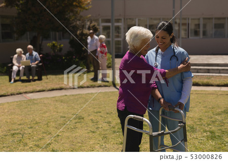 Young female doctor helping disabled senior woman in garden Young female doctor helping disabled senior woman in garden 53000826