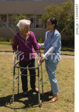 Young female doctor helping disabled senior woman in garden Young female doctor helping disabled senior woman in garden 53000897