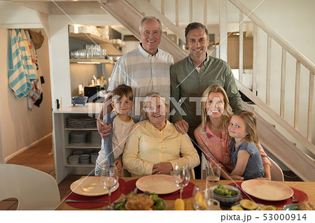 Family posing together before having meal on dining table Family posing together before having meal on dining table 53000914