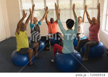 Female trainer training senior people in performing exercise 53000918