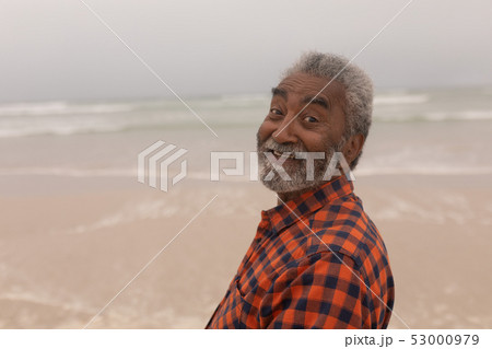 Happy senior man looking at camera on beach Happy senior man looking at camera on beach 53000979