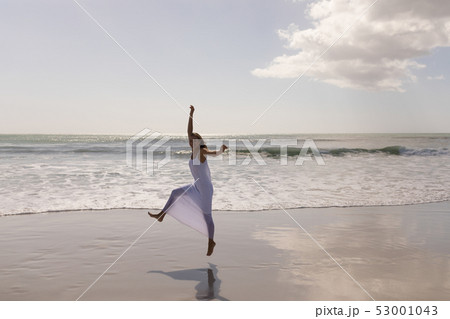 Young woman jumping and having fun on beach Young woman jumping and having fun on beach 53001043