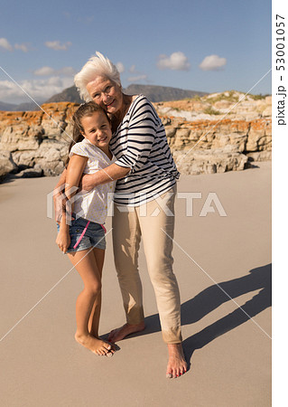 Happy senior woman embracing her granddaughter on beach 53001057