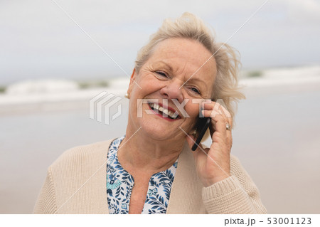 Happy senior woman talking on mobile phone at beach Happy senior woman talking on mobile phone at beach 53001123