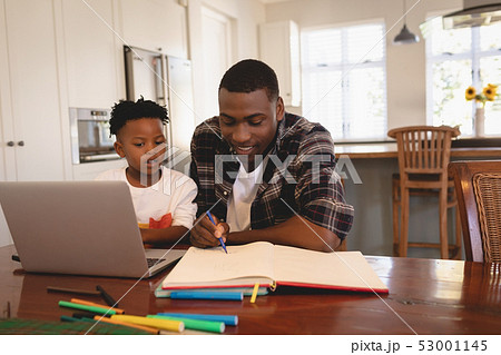 African American father helping his son with homework at table 53001145