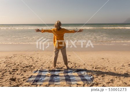 Senior woman standing with arms outstretched on the beach Senior woman standing with arms outstretched on the beach 53001273
