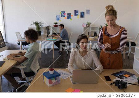 Female executives discussing over laptop at desk Female executives discussing over laptop at desk 53001277