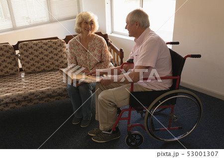 Senior couple looking at photo album in living room Senior couple looking at photo album in living room 53001307