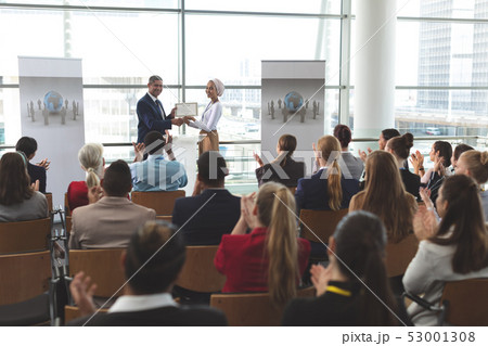 Businesswoman receiving award from businessman in a business seminar Businesswoman receiving award from businessman in a business seminar 53001308