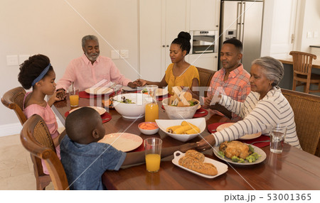 Multi-generation family praying together before having meal 53001365