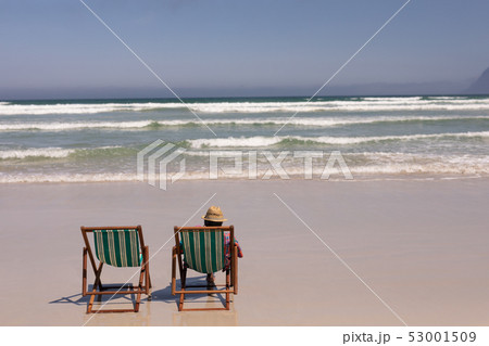 Senior man relaxing on sun lounger on beach 53001509