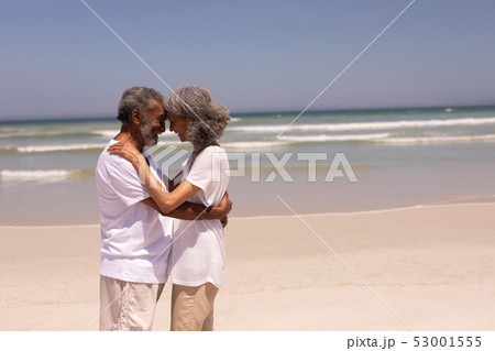 Senior couple head to head and embracing each other on beach 53001555