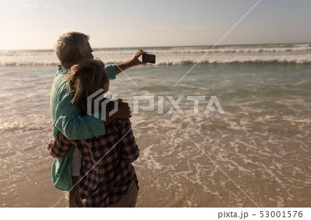 Senior couple taking selfie with mobile phone on the beach 53001576