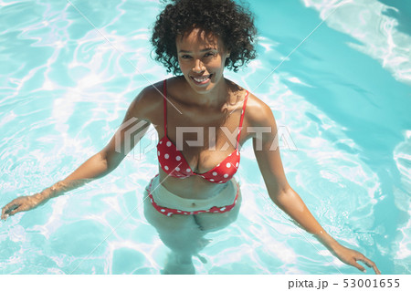Happy young African American man looking at camera in swimming pool Happy young African American man looking at camera in swimming pool 53001655
