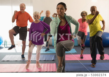 Front view of female trainer assisting senior people in fitness studio Front view of female trainer assisting senior people in fitness studio 53002374
