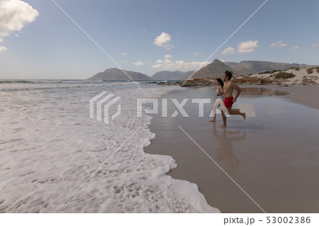 Young couple running and having fun at beach 53002386