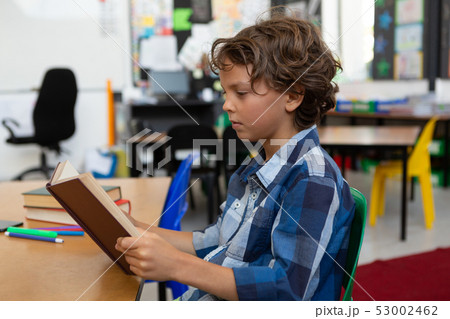 Schoolboy reading a book in the classroom 53002462