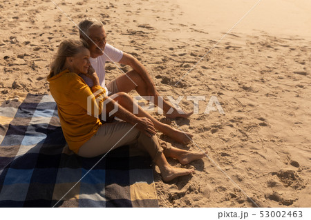 Senior couple relaxing on picnic blanket at beach 53002463