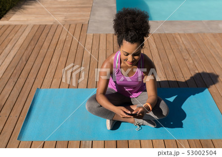 Woman using mobile phone in the backyard of home Woman using mobile phone in the backyard of home 53002504