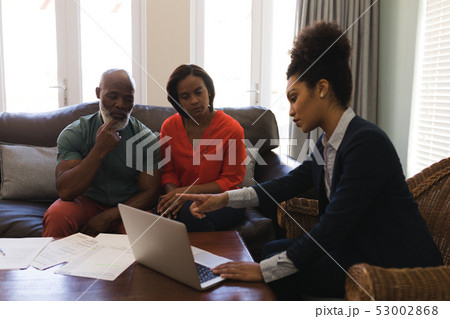 Female real estate agent and senior couple discussing over laptop Female real estate agent and senior couple discussing over laptop 53002868