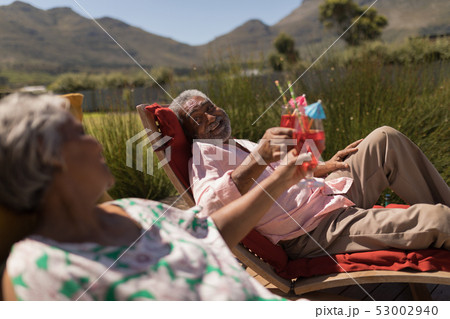 Senior couple toasting glasses of cocktail in the backyard of home 53002940