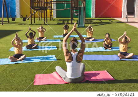 Trainer teaching yoga to students in school playground 53003221